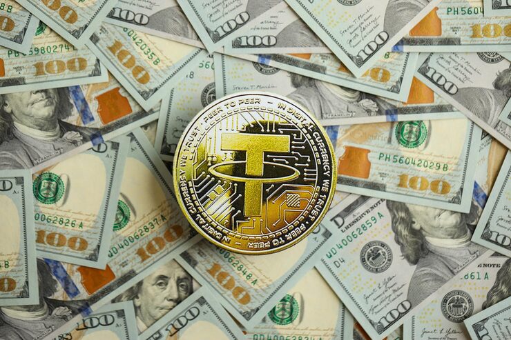 เหรียญทองคำจำลองสัญลักษณ์คริปโต Tether USDT วางบนกองธนบัตรดอลลาร์สหรัฐสำหรับภาพปก Stablecoin คืออะไร